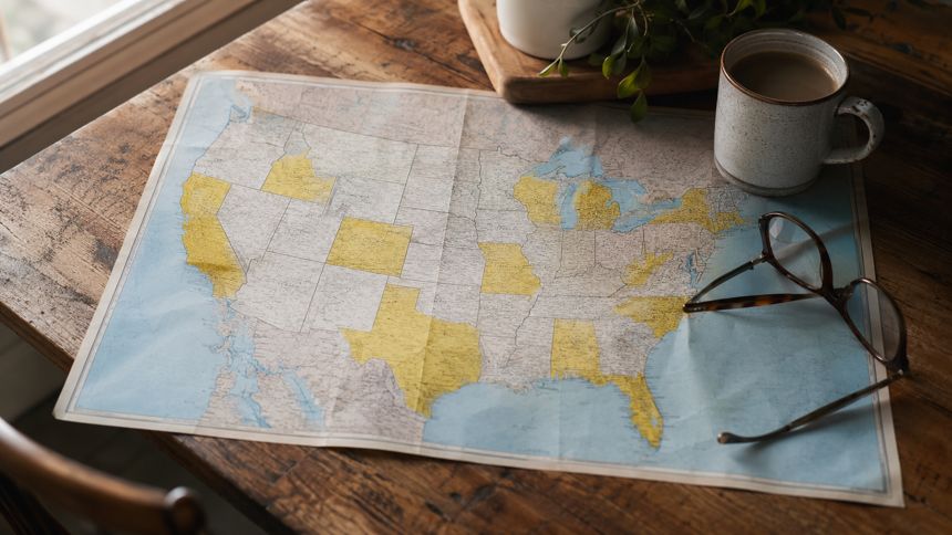 Printed map of the United States on a kitchen table with reading glasses and coffee